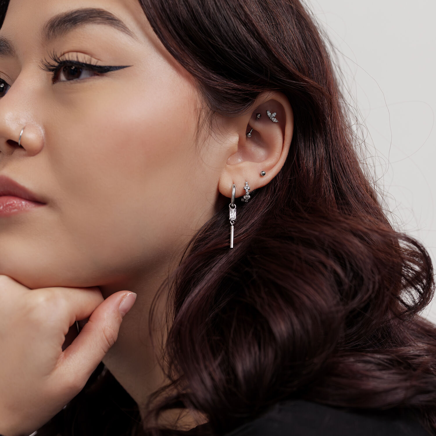 Mujer con pequeños pendientes de cristal cuadrados sobre fondo blanco