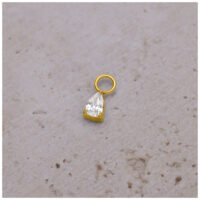 Colgante de piercing dorado con gota de cristal sobre fondo claro