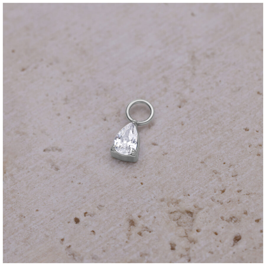 Colgante de gota plateado con cristal sobre fondo beige