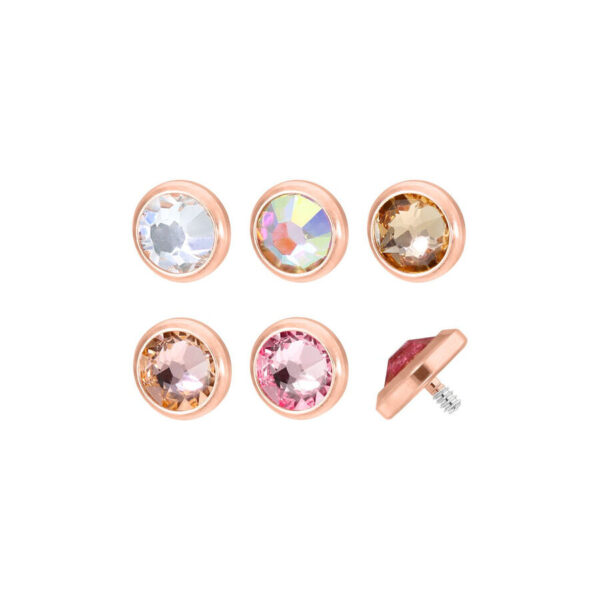 Seis accesorios de piercing en oro rosa con cristales claros y de colores sobre fondo blanco