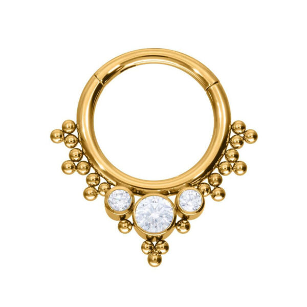 Anillo de piercing dorado con tres cristales claros sobre fondo blanco