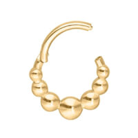 Aro de piercing dorado con diseño de bolas sobre fondo blanco