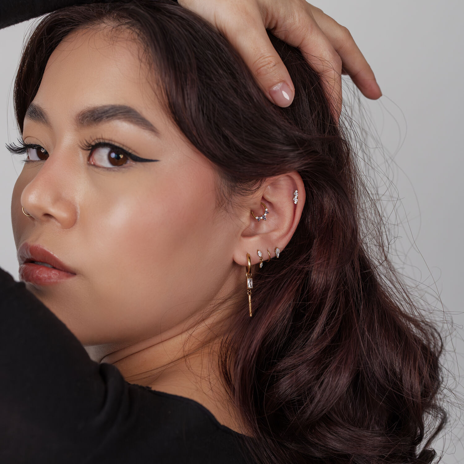 Mujer con varios pendientes, clicker de septum dorado con cristales de lavanda