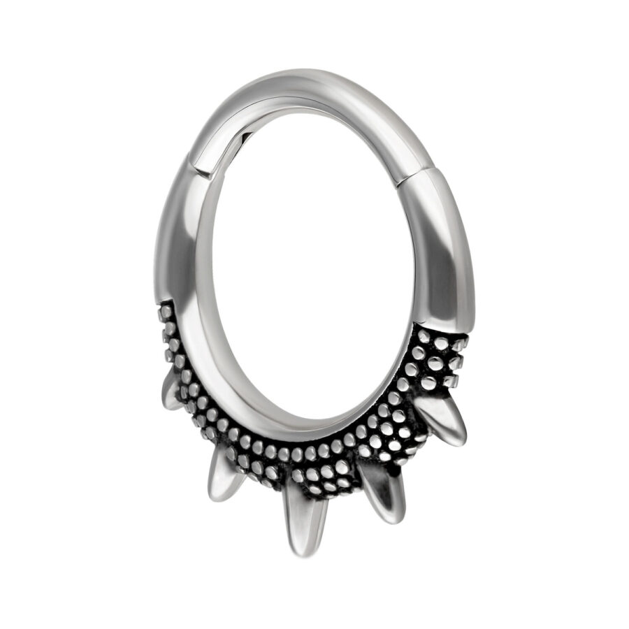 Anillo de piercing plateado y negro con diseño de picos sobre fondo blanco