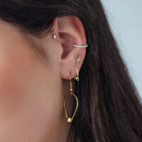 Accesorio Push Dorado con Cristal Ovalado en la Oreja con otros piercings dorados