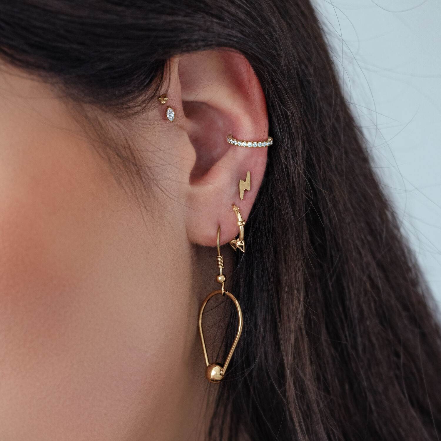 Accesorio Push Dorado con Cristal Ovalado en la Oreja con otros piercings dorados