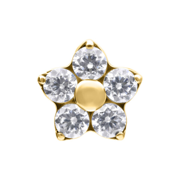 Aplique de flor dorado con cinco cristales claros sobre fondo blanco