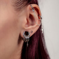 Primer plano de una oreja con Push Fit plateados y detalles de cadenas