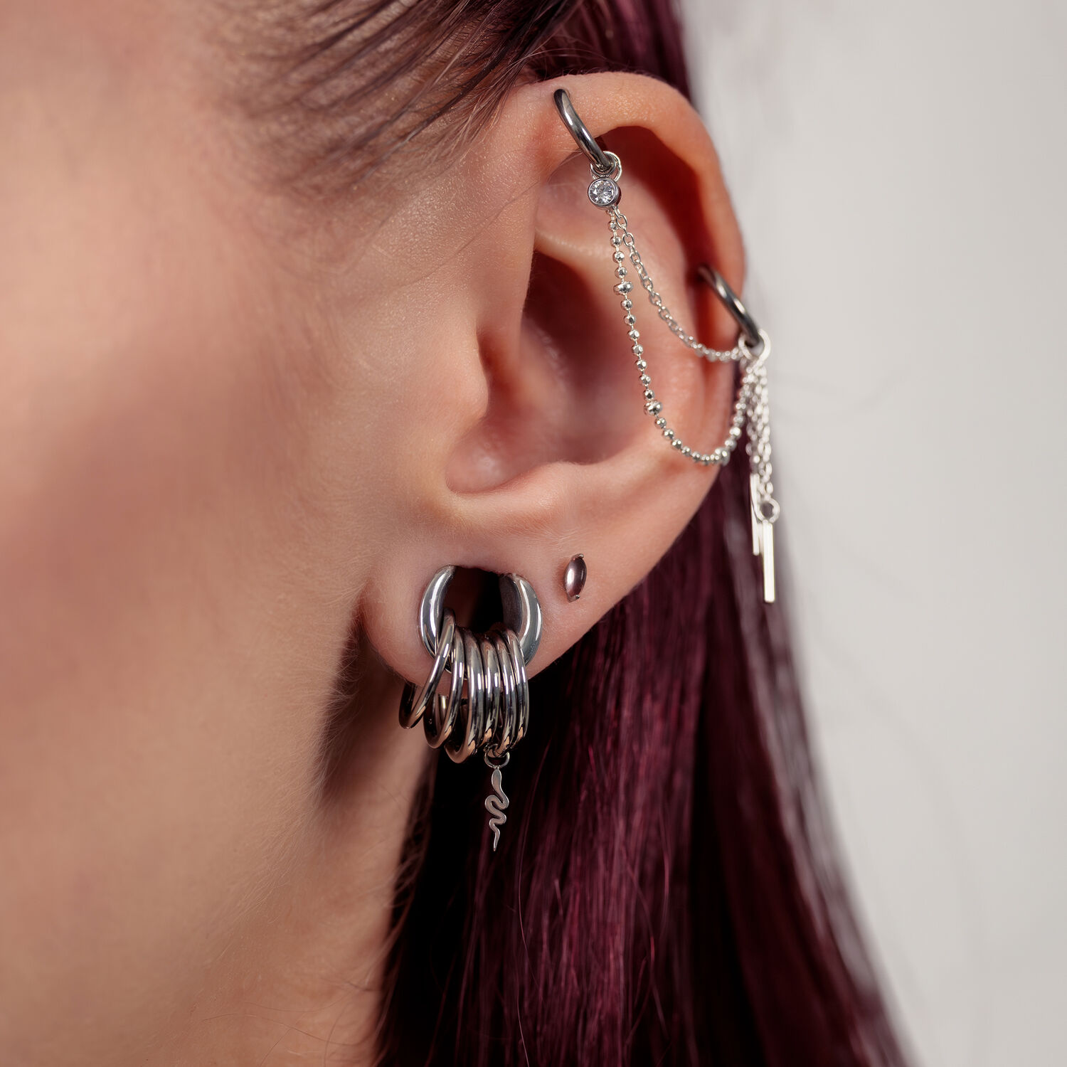 Primer plano de una oreja con Push Fit plateados y detalles de cadenas