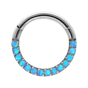 Anillo de piercing plateado con piedras de opalo azul claro sobre fondo blanco