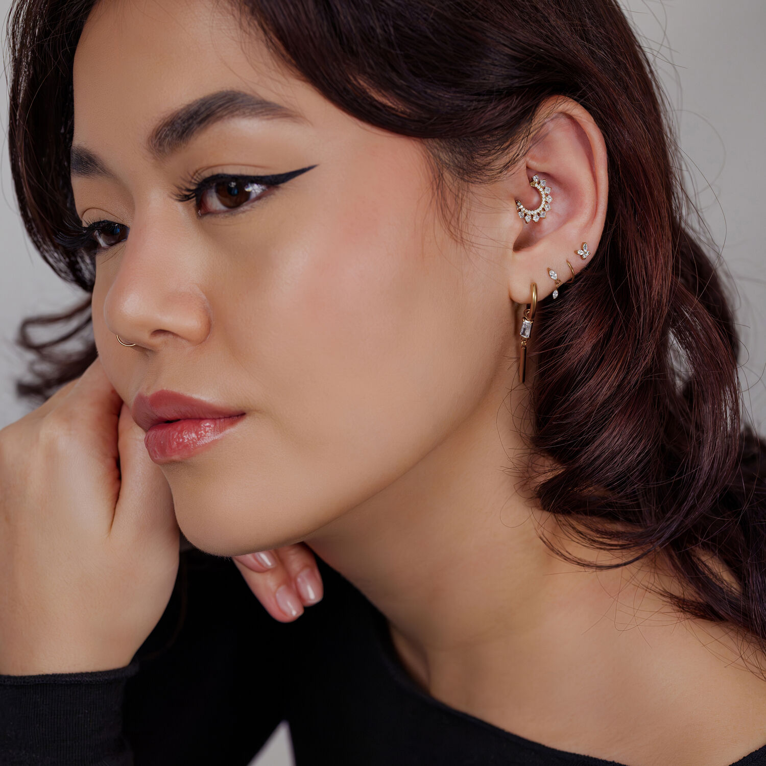 Mujer con múltiples pendientes, pendiente de cristal dorado y blusa negra