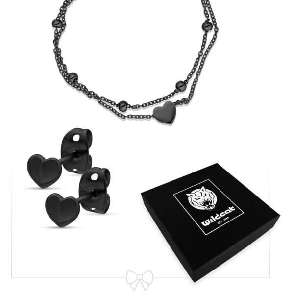 Conjunto de joyas negras con motivo de corazón de acero quirúrgico, compuesto por collar y pendientes, sobre fondo blanco