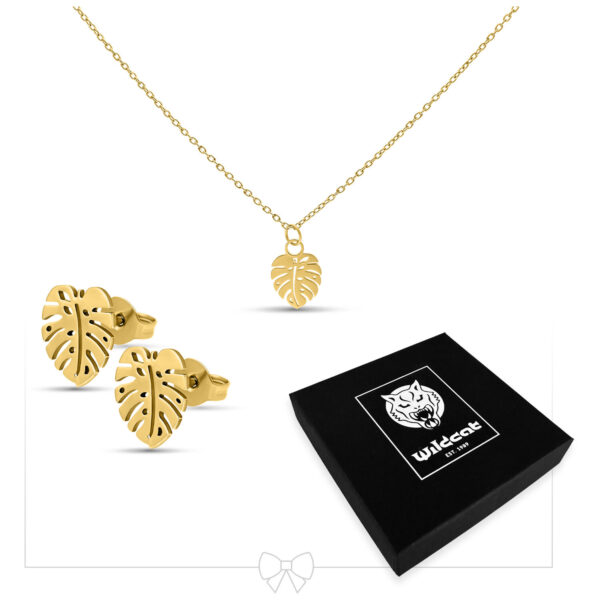 Pendientes y collar Monstera dorados con colgante de hoja frente a una caja negra