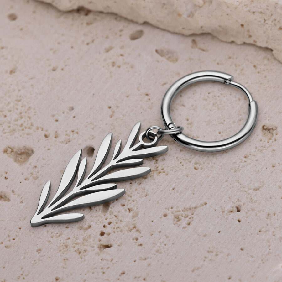 Pendiente de plata con diseño de rama sobre superficie de piedra beige