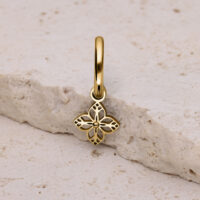 Pendiente dorado con adorno floral Pendiente dorado con delicado adorno floral sobre piedra clara