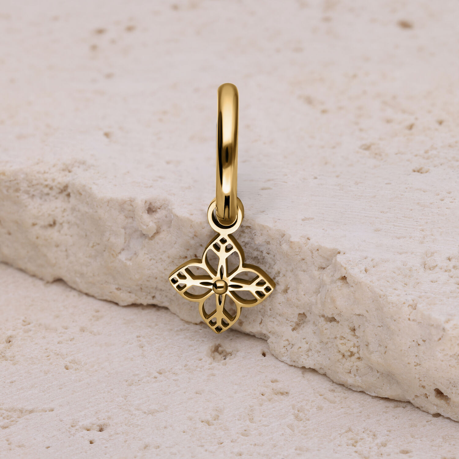 Pendiente dorado con adorno floral Pendiente dorado con delicado adorno floral sobre piedra clara