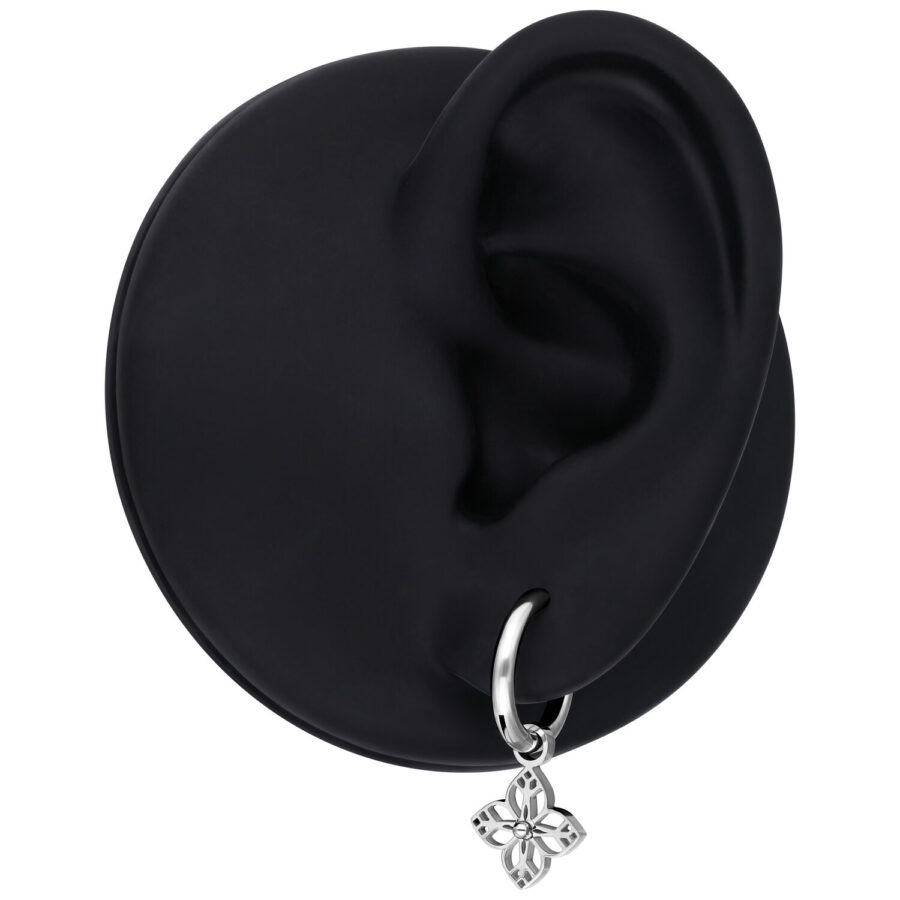 Pendiente de plata con pequeño colgante de flor, presentado en un modelo de oreja negra