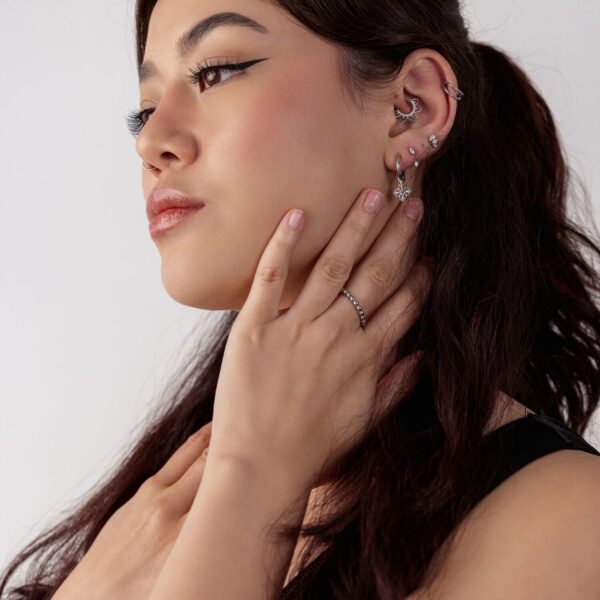Mujer con varios pendientes plateados, decorados con flores, perfil lateral