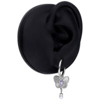 Pendiente plateado con colgante de mariposa lila y perla en un modelo de oreja negra