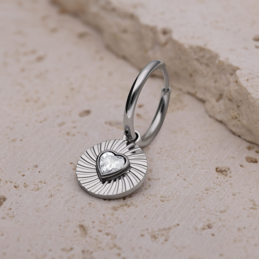 Pendiente de plata con colgante en forma de corazón sobre piedra clara