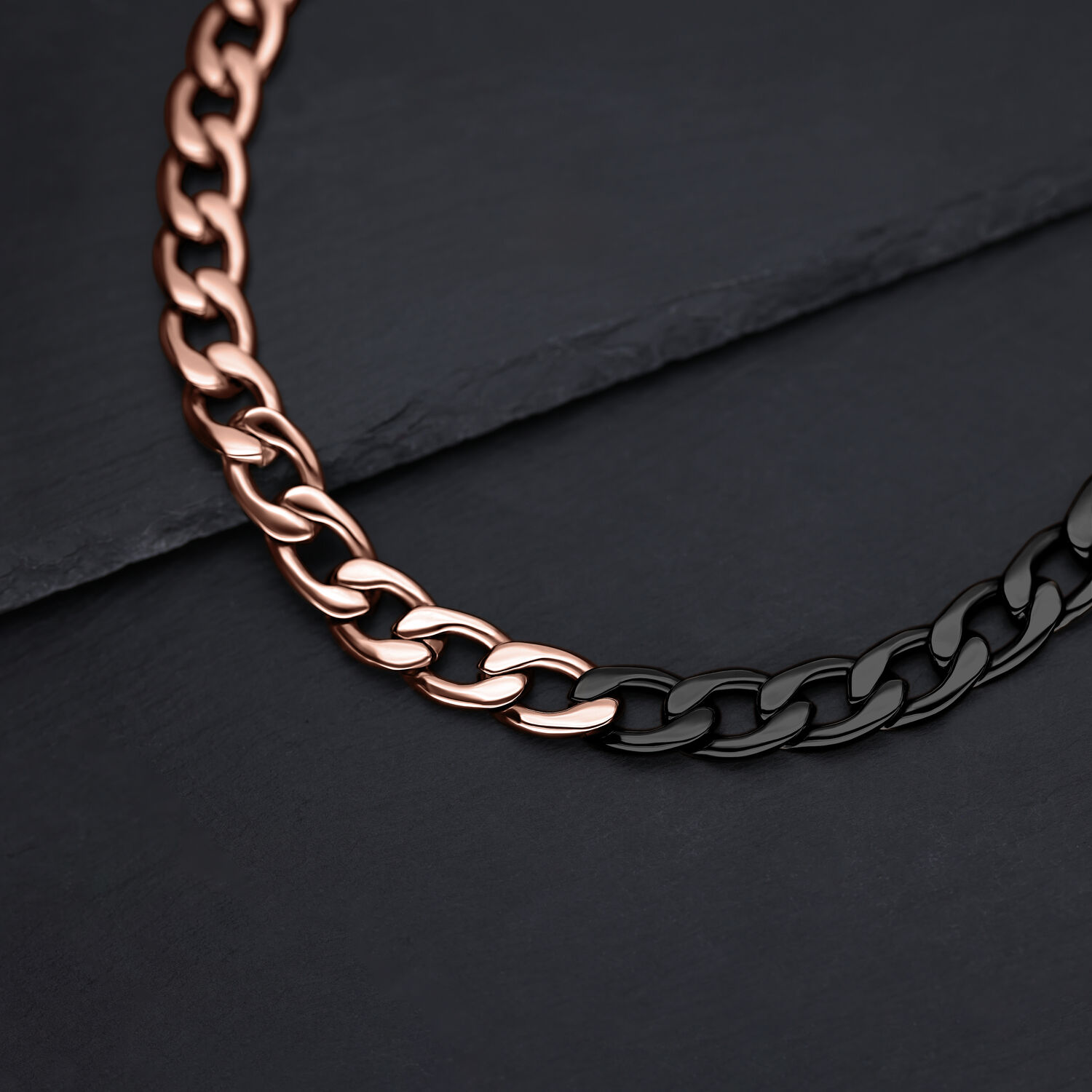 Collar de eslabones rosa oro y negro sobre fondo de pizarra oscura