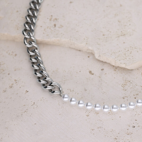 Collar de eslabones plateados combinado con perlas sintéticas sobre fondo de piedra clara