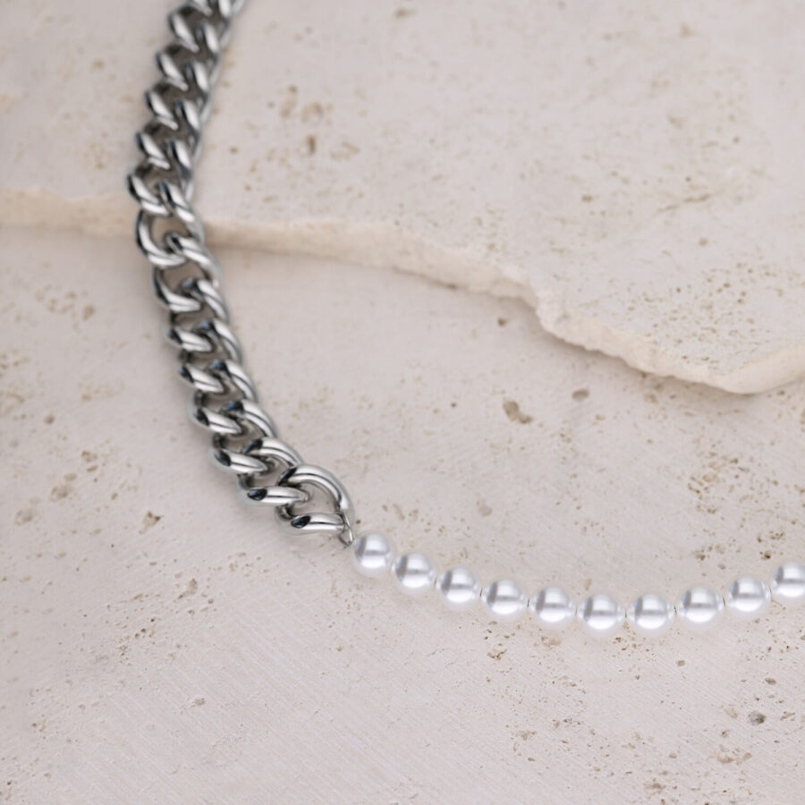 Collar de eslabones plateados combinado con perlas sintéticas sobre fondo de piedra clara