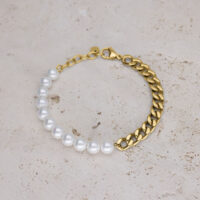 Pulsera con perlas sintéticas blancas y cadena de eslabones dorada sobre fondo beige