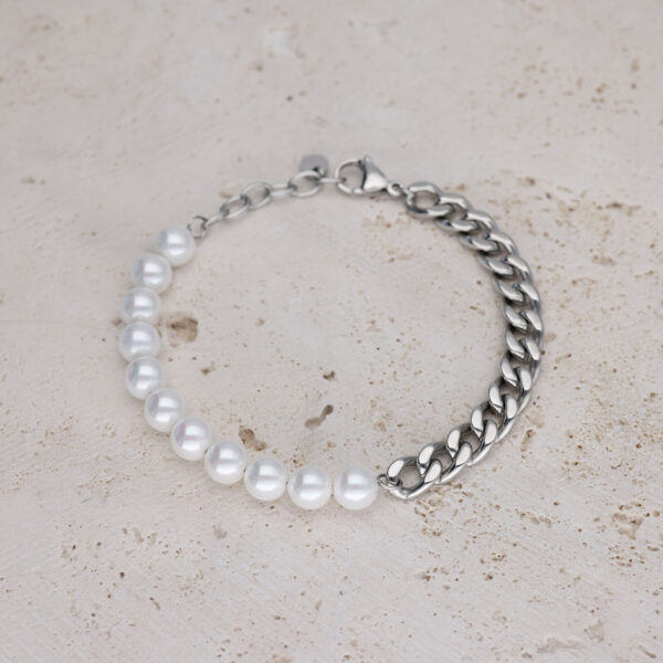 Pulsera con perlas blancas y cadena plateada sobre piedra clara