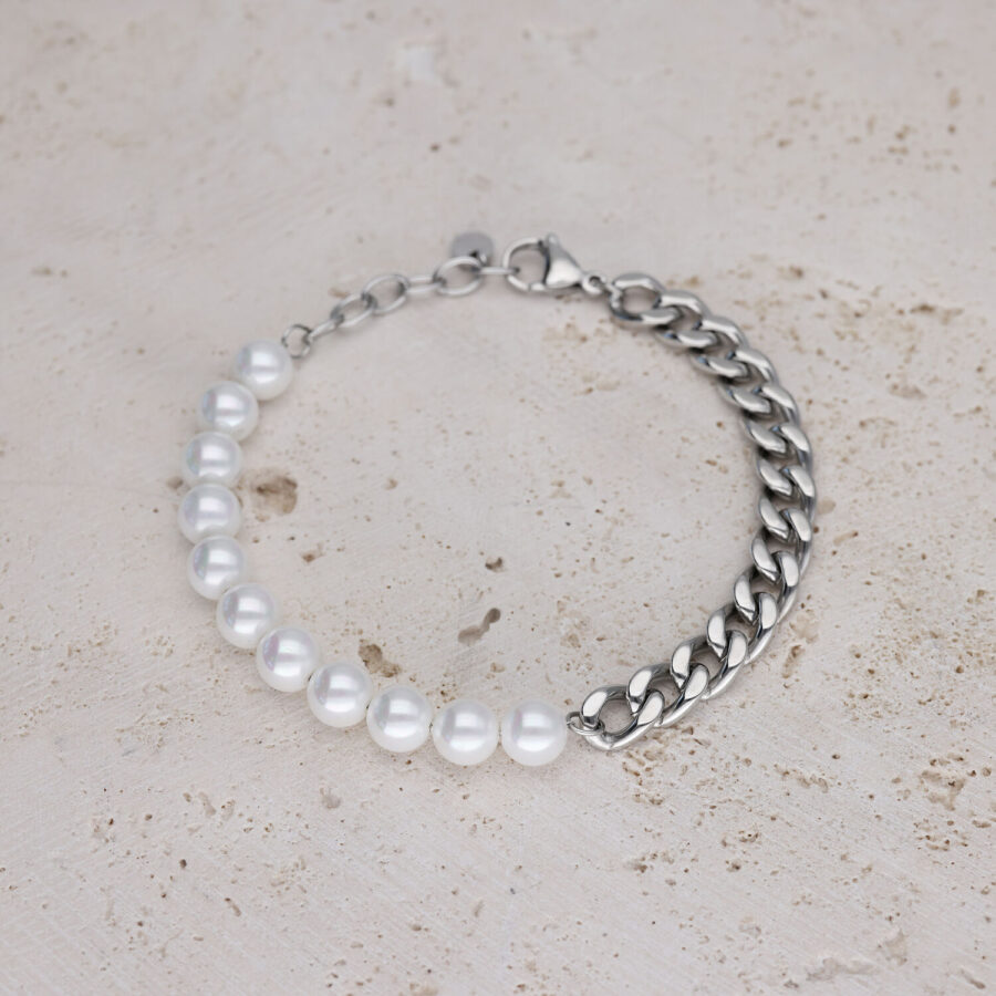 Pulsera con perlas blancas y cadena plateada sobre piedra clara