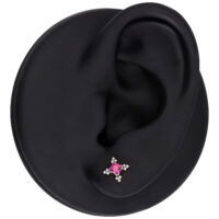 Modelo de oreja con accesorio de piercing plateado y cristal rojo sobre fondo negro