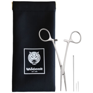 Pinza de piercing plateada y agujas junto a bolsa negra con logo de Wildcat
