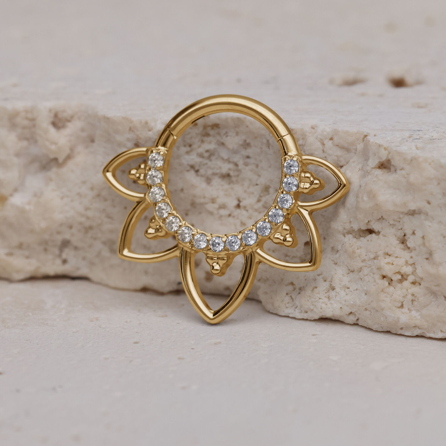 Clicker de septum dorado con cristales sobre superficie de piedra clara