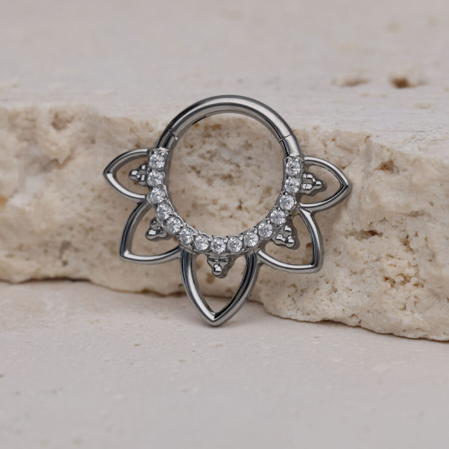 Clicker de septum plateado con cristales claros sobre piedra clara