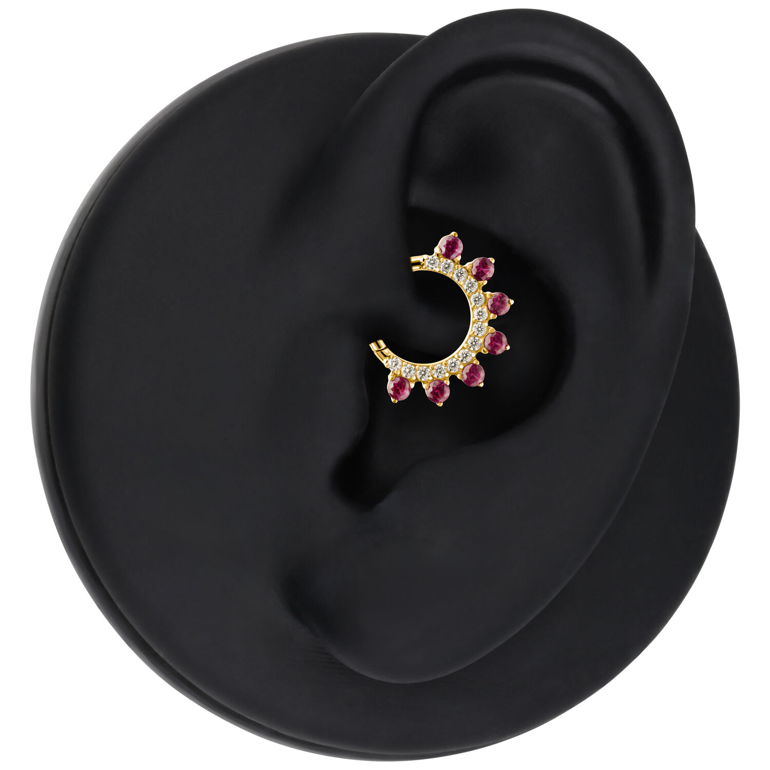 Pendiente dorado con cristales rojos colocado en un modelo de oreja negra