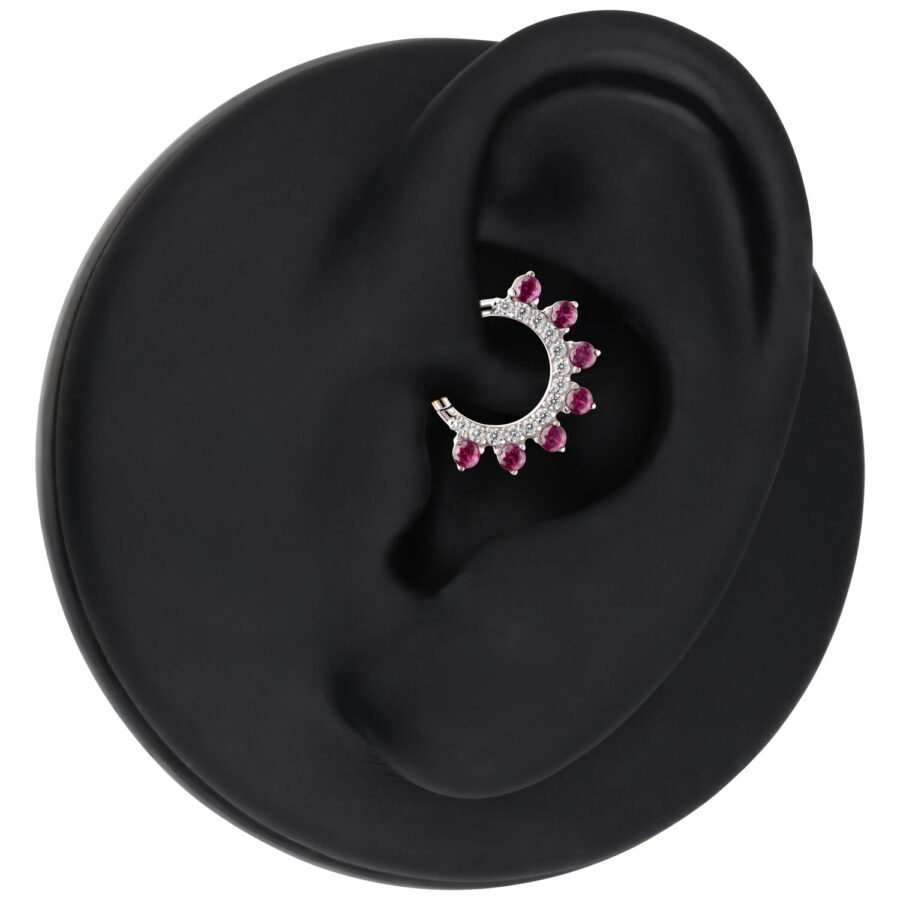 Anillo de piercing plateado con cristales rojos en un expositor de oreja negro