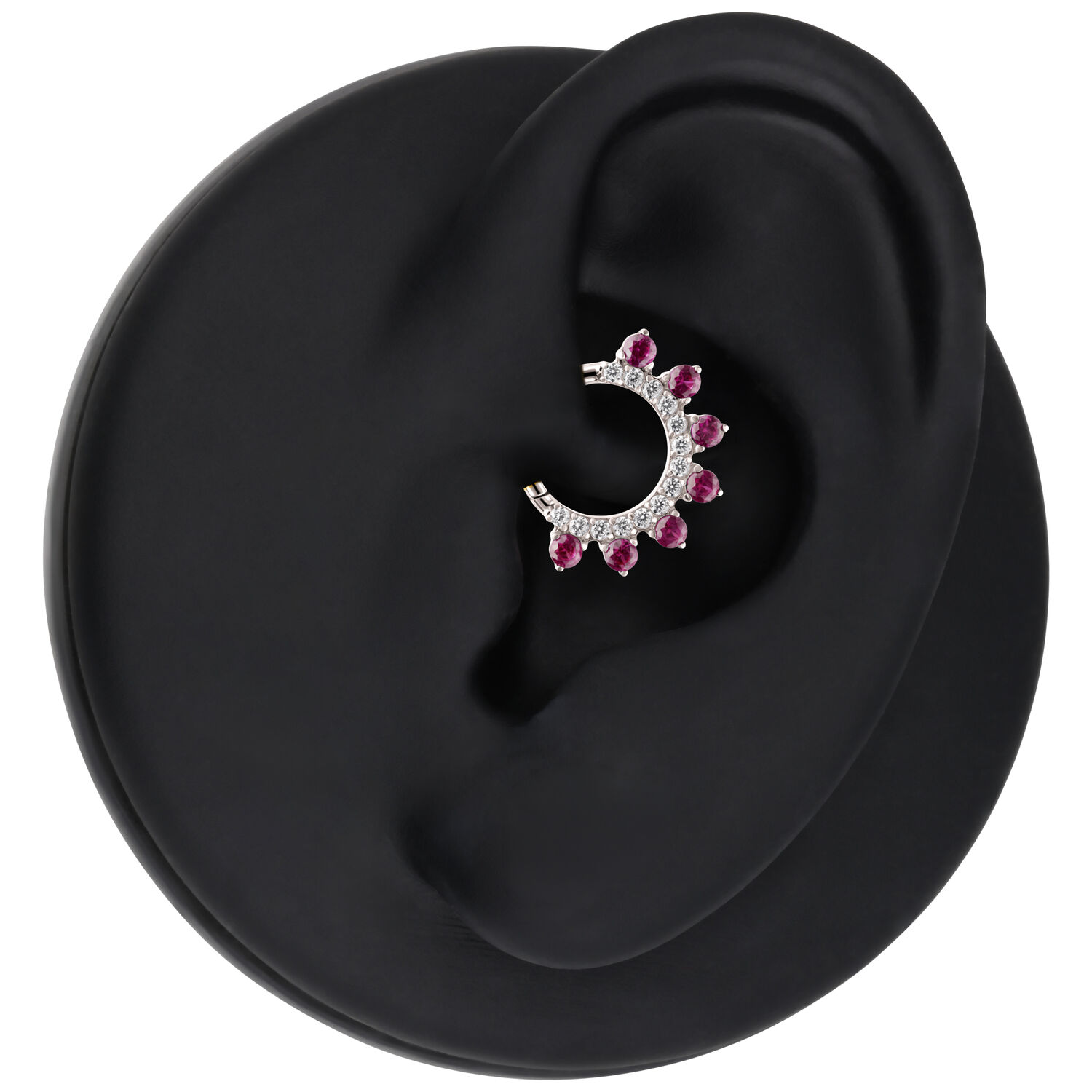 Anillo de piercing plateado con cristales rojos en un expositor de oreja negro