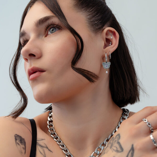 Mujer con aros de mariposa plateados, primer plano