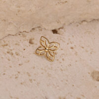 Aplique de flor dorada sobre fondo de piedra beige