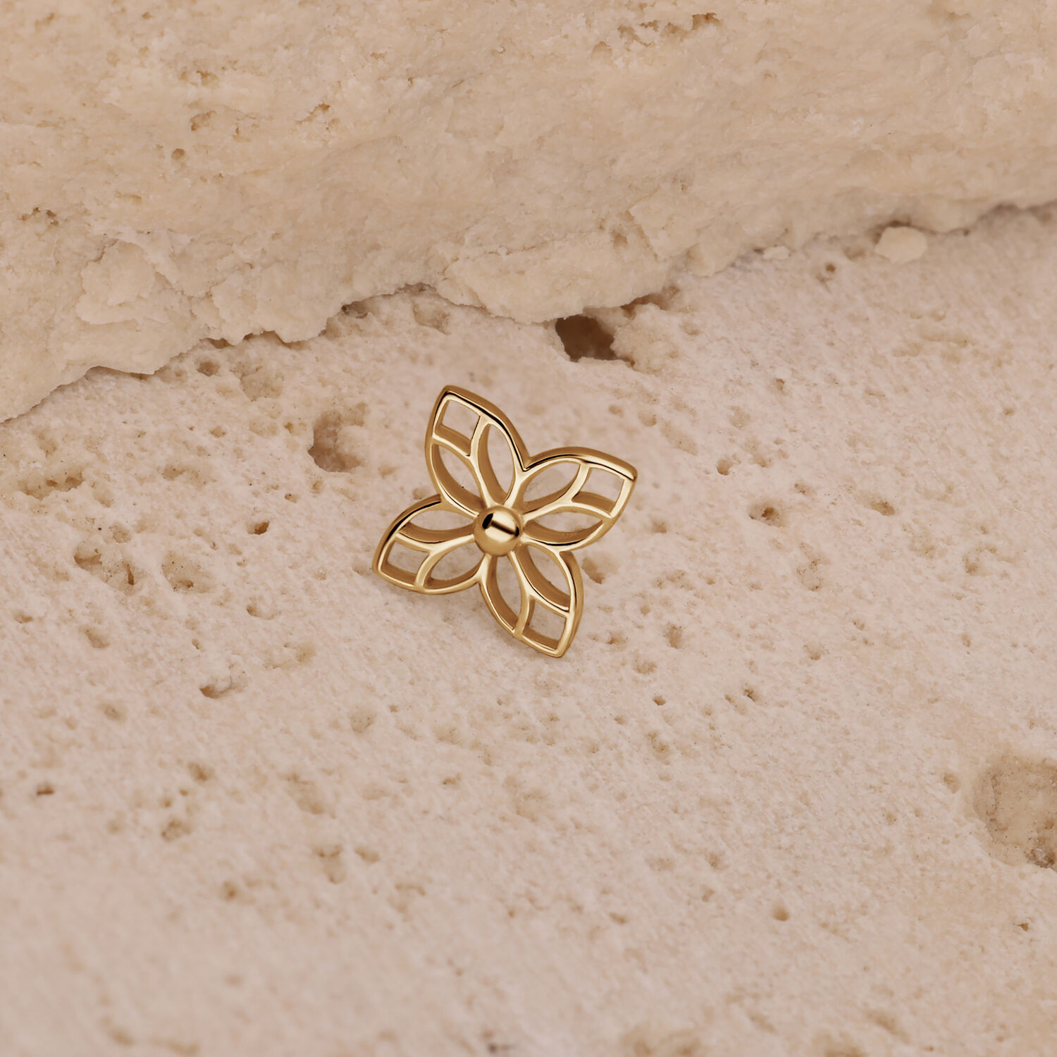 Aplique de flor dorada sobre fondo de piedra beige