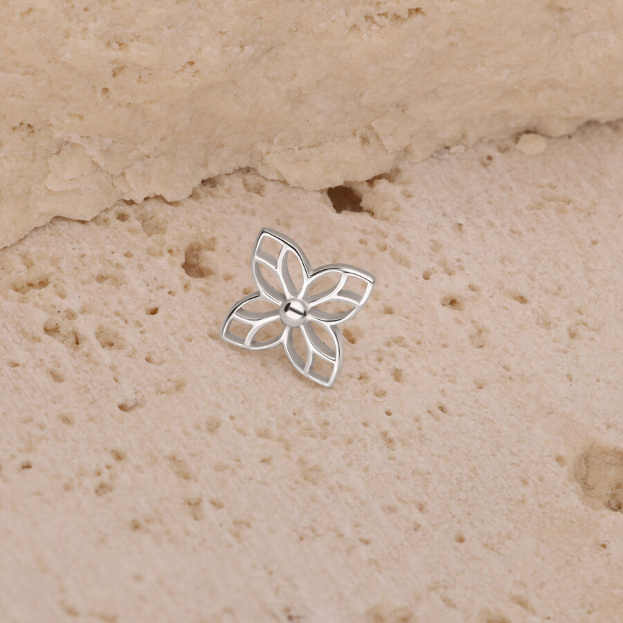 Aplique de flores plateado sobre una superficie beige y texturizada