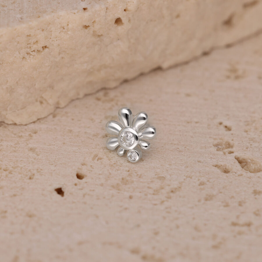 Ajuste Push de plata con piedra cristalina sobre superficie beige