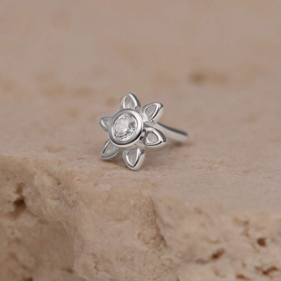 Ajuste de flor plateada con cristal sobre piedra beige