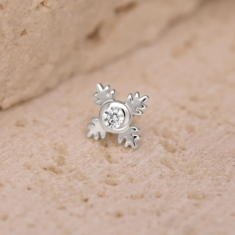 Accesorio de piercing Push Fit plateado en forma de hoja con cristal claro sobre fondo arenoso