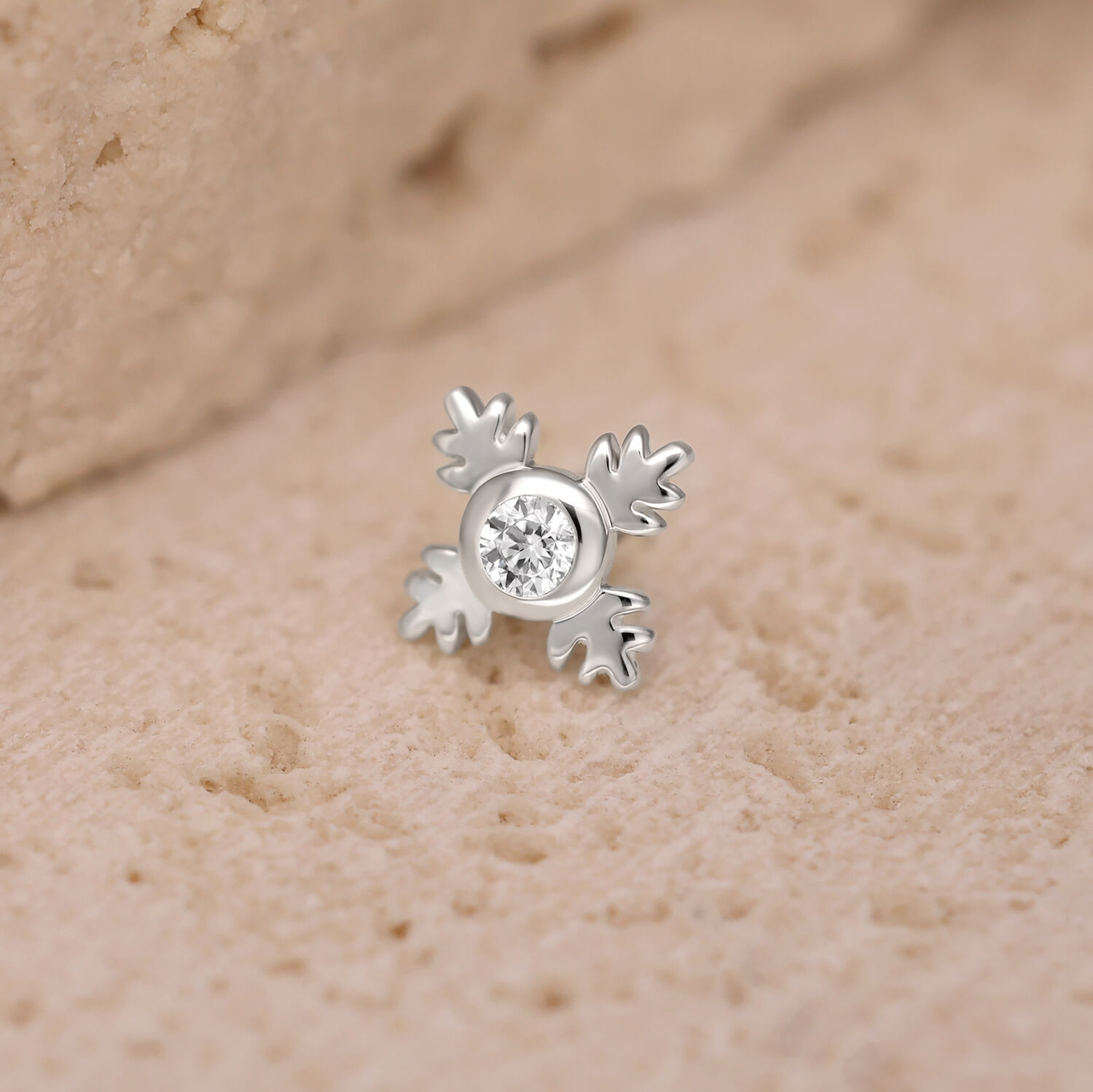 Accesorio de piercing Push Fit plateado en forma de hoja con cristal claro sobre fondo arenoso