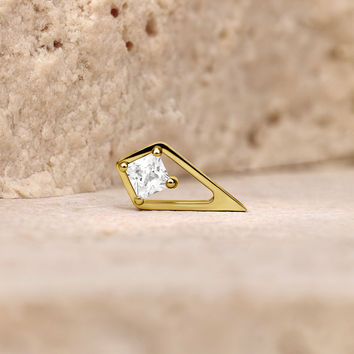 Ajuste Push de Oro con cristal claro sobre fondo color piedra