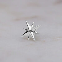 Aplique en forma de estrella de oro blanco sobre fondo de mármol blanco