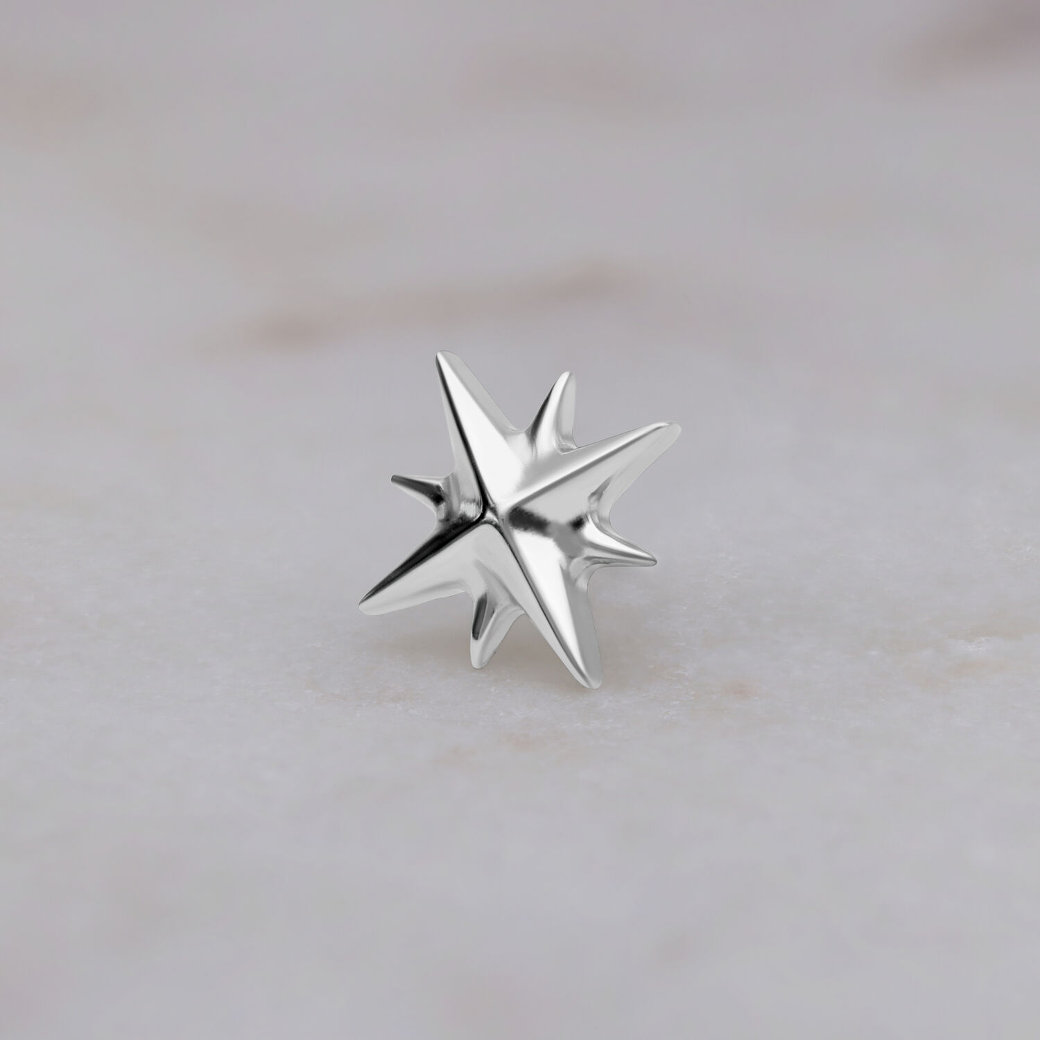 Aplique en forma de estrella de oro blanco sobre fondo de mármol blanco