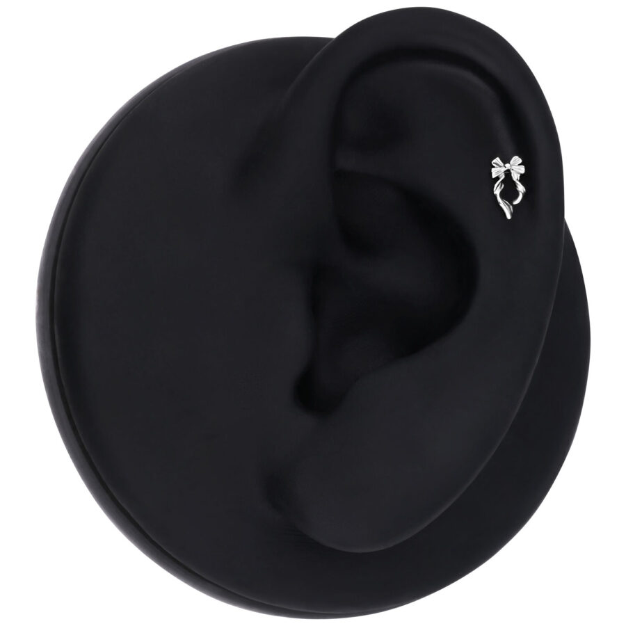 Modelo de oreja negra con piercing de lazo plateado sobre fondo negro
