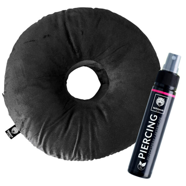 Cojín redondo negro para piercing de poliéster con agujero central, junto a una botella de spray para cuidado de piercings sobre fondo blanco
